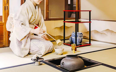 Person performing traditional Japanese tea ceremony with matcha tools.
