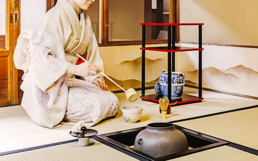 Person performing traditional Japanese tea ceremony with matcha tools.