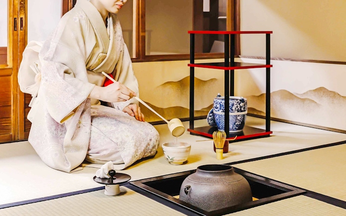 Person performing traditional Japanese tea ceremony with matcha tools.