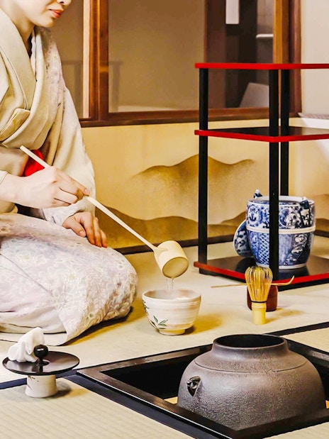 Person performing traditional Japanese tea ceremony with matcha tools.