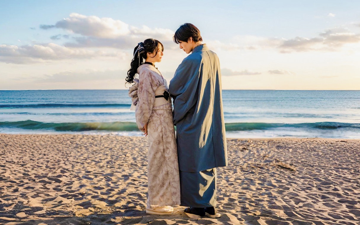 Couple in traditional Kimono posing on a beach at sunset.