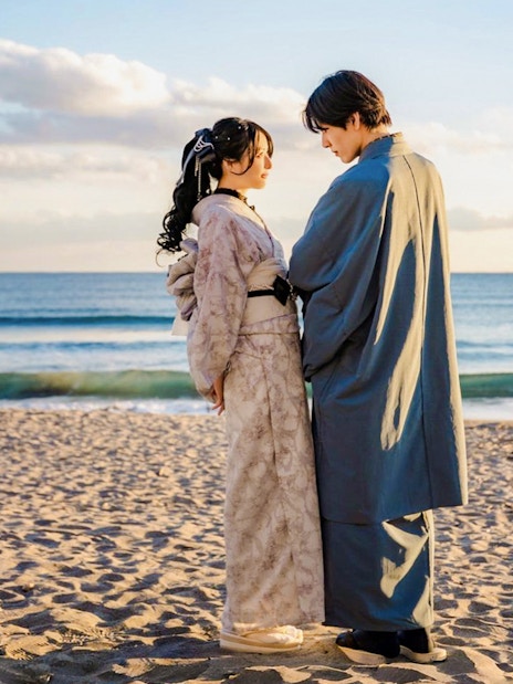 Couple in traditional Kimono posing on a beach at sunset.