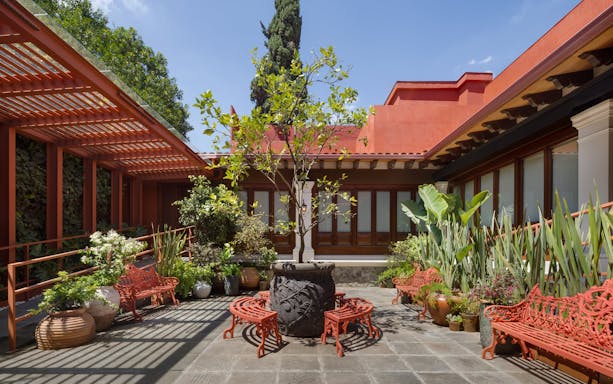 Courtyard with red benches and plants at Museo Casa Kahlo, Mexico City.