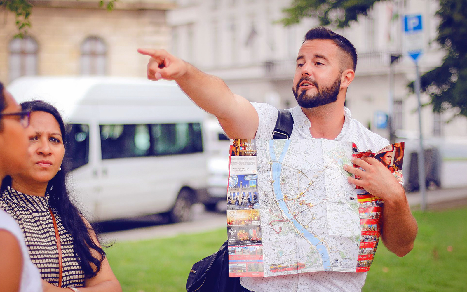 Tour guide pointing while holding a map during a guided bus tour in Budapest.