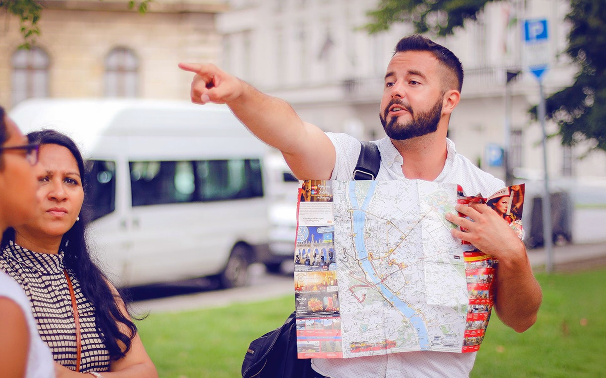 Tour guide pointing while holding a map during a guided bus tour in Budapest.