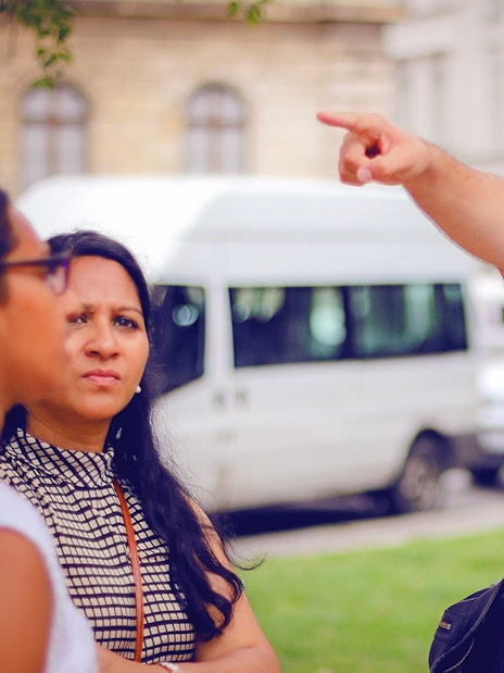 Tour guide pointing while holding a map during a guided bus tour in Budapest.