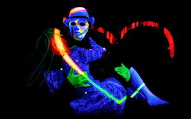 Performers in neon costumes at black light theatre, Prague.