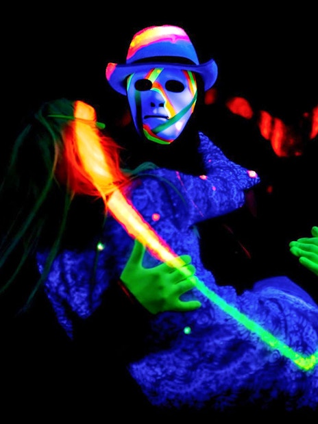 Performers in neon costumes at black light theatre, Prague.