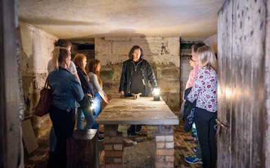 Guide leading a group in a dimly lit room during Port Arthur Historic Site Ghost Tour.