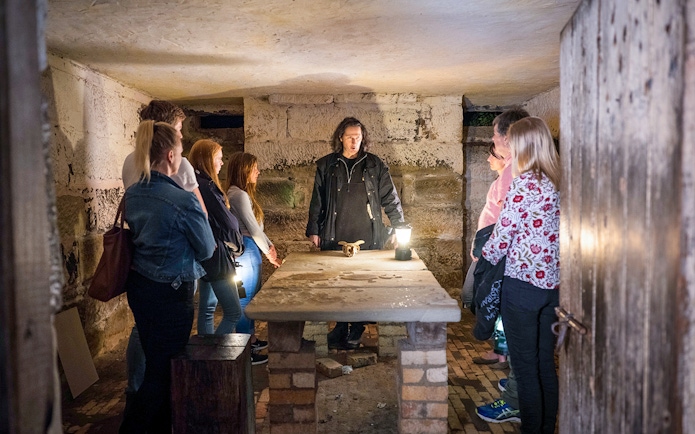 Guide leading a group in a dimly lit room during Port Arthur Historic Site Ghost Tour.
