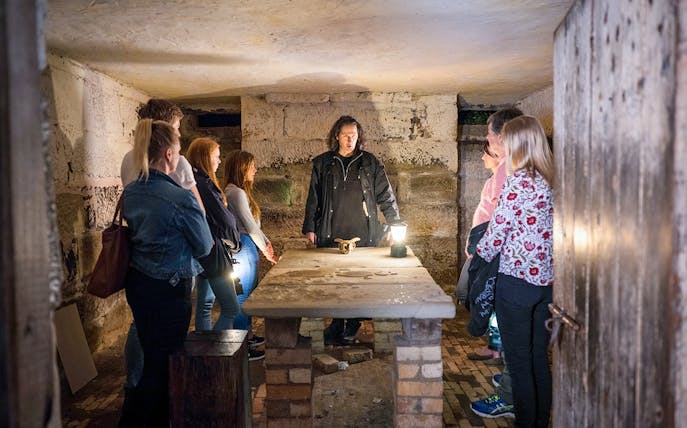 Guide leading a group in a dimly lit room during Port Arthur Historic Site Ghost Tour.