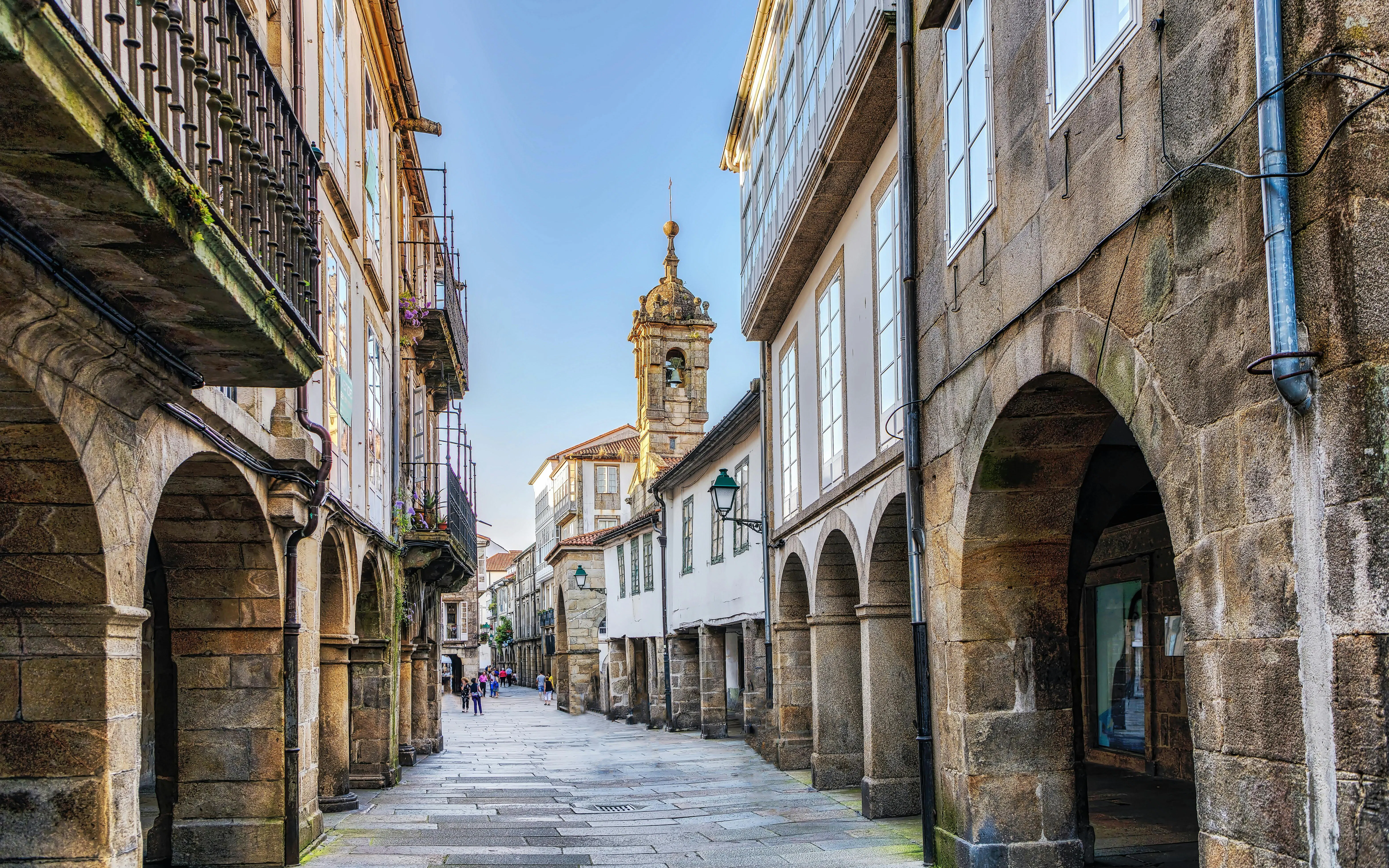 Narrow cobblestone street with arched buildings in Old Town Santiago de Compostela, Galicia, Spain.