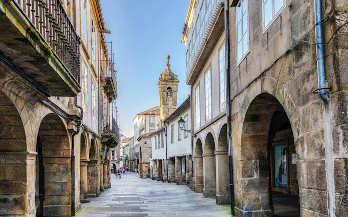 Narrow cobblestone street with arched buildings in Old Town Santiago de Compostela, Galicia, Spain.