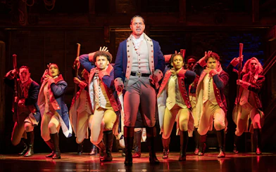 Cast performing a scene from Hamilton in West End theater.