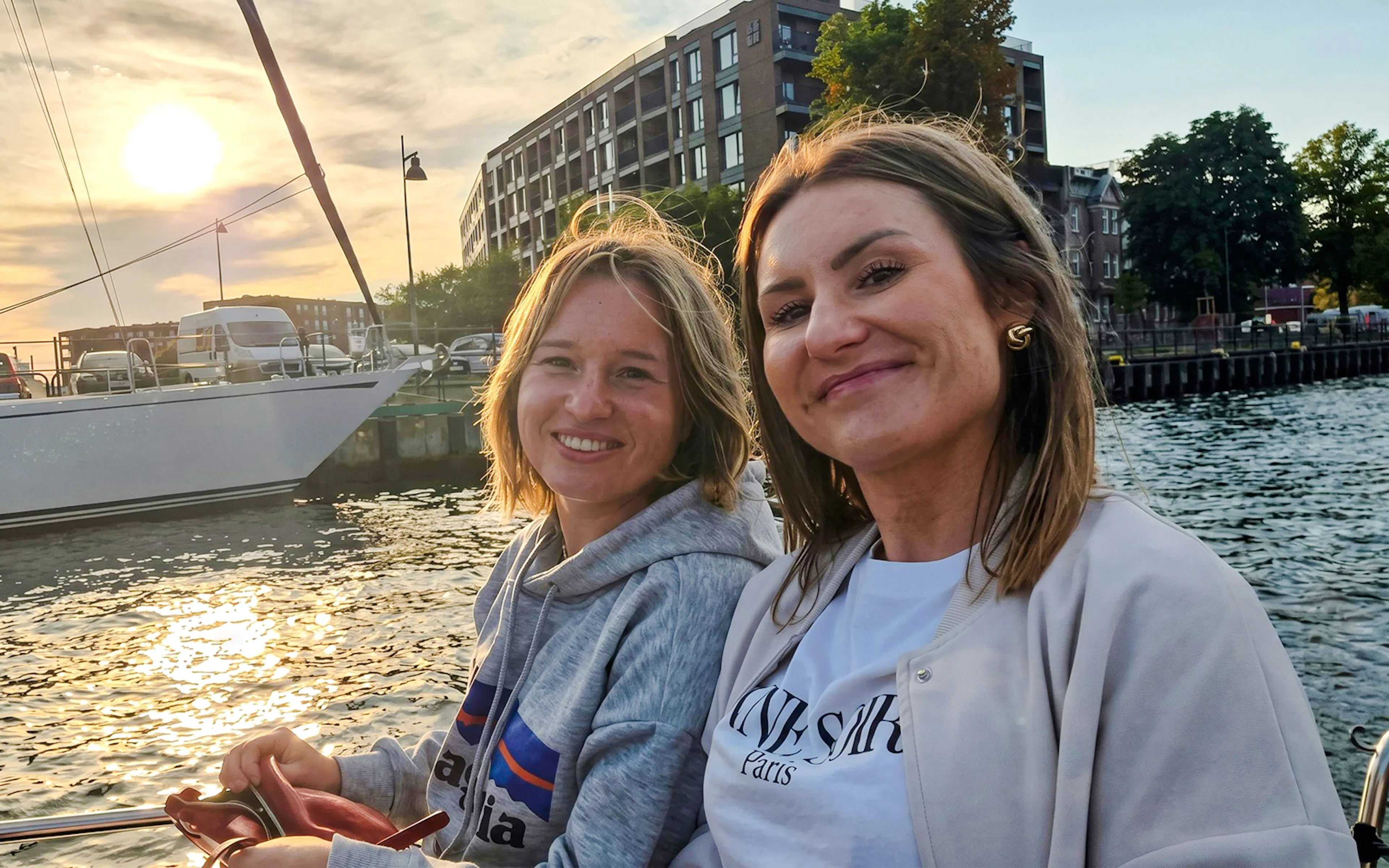 Guests smiling on Gdańsk Scenic Cruise with sunset and waterfront views.