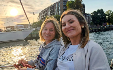 Guests smiling on Gdańsk Scenic Cruise with sunset and waterfront views.