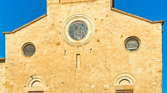 San Gimignano Cathedral facade with stone steps under clear blue sky.