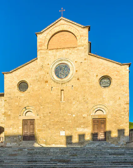 San Gimignano Cathedral facade with stone steps under clear blue sky.