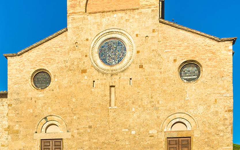 San Gimignano Cathedral facade with stone steps under clear blue sky.