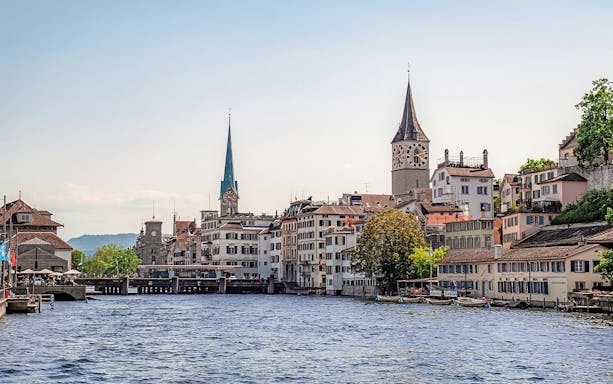 Zurich cityscape with historic buildings and church towers along the Limmat River.