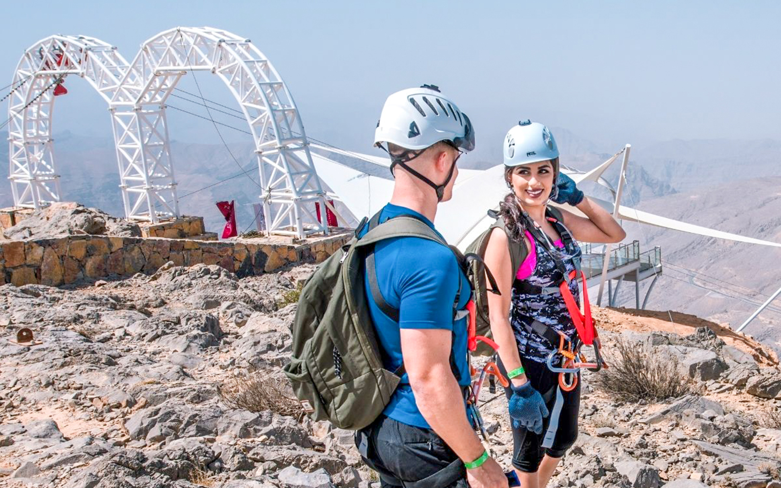 Two people in helmets and harnesses at Jais Flight zipline, UAE.
