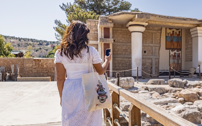 Woman exploring Knossos Palace with self-guided audio tour in English, French, and Italian.