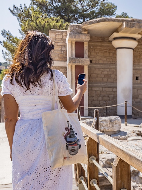 Woman exploring Knossos Palace with self-guided audio tour in English, French, and Italian.
