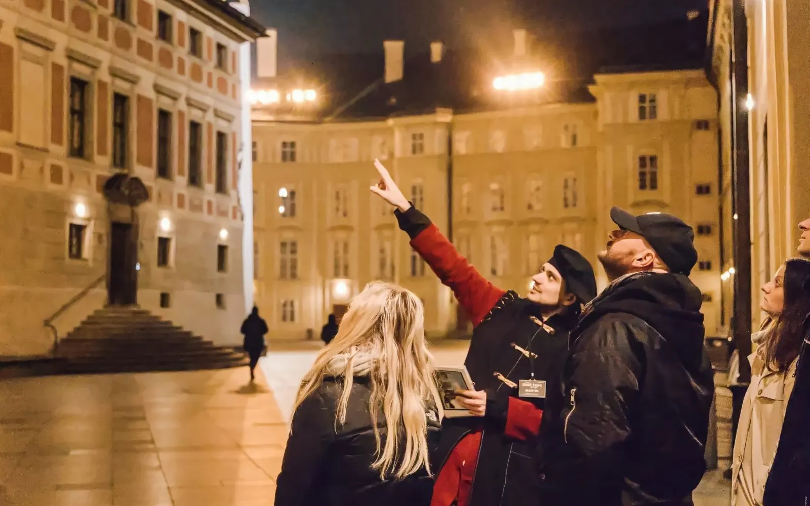 Tour guide pointing at Prague Castle during night tour with group.