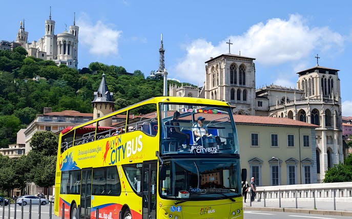 Lyon city tour bus passing by Basilica of Notre-Dame de Fourvière, France.