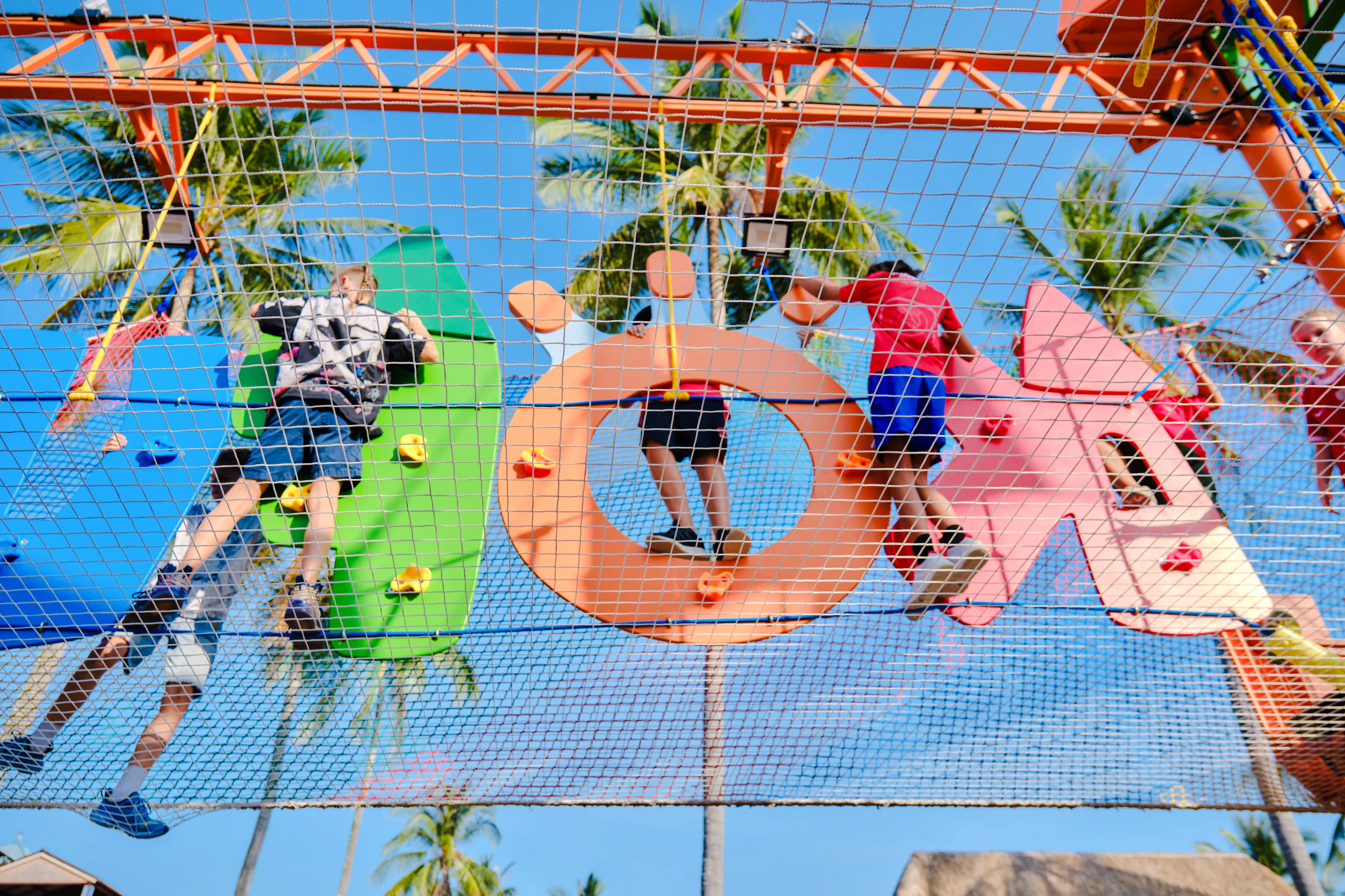Children climbing colorful obstacle course at outdoor adventure park in Phuket.