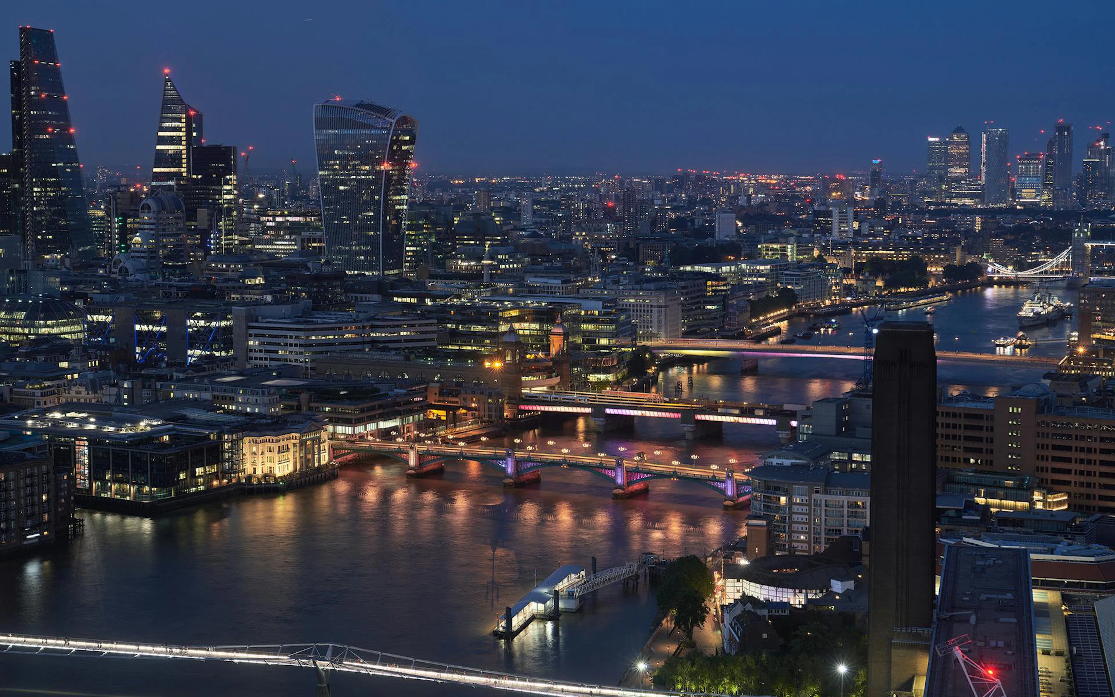 London skyline at night with illuminated bridges over the River Thames during a boat tour.