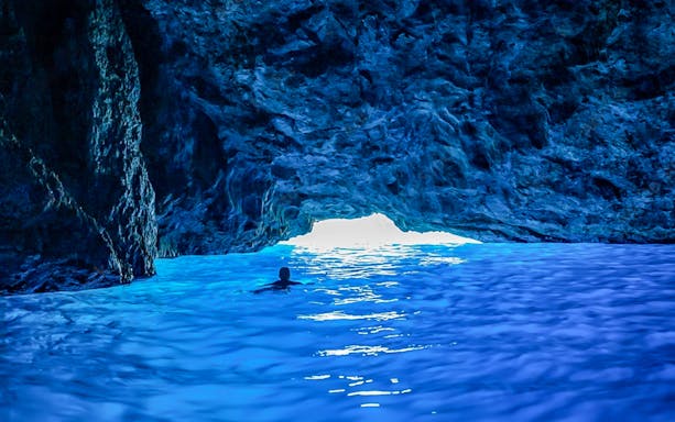 Visitors swimming in the vibrant waters of the Blue Caves, Zakynthos, Greece.