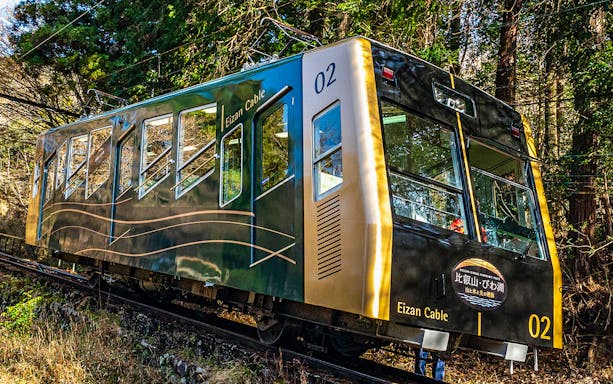 Eizan Cable car traveling through forested area in Kyoto's Kurama and Kibune region.