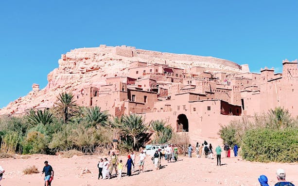 Ait Benhaddou kasbah with tourists walking, part of 3 Days Desert Tour to Merzouga Dunes.