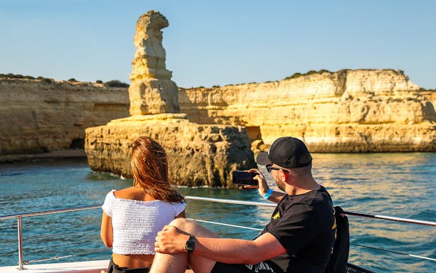 Sightseeing cruise passengers view Algarve's coastal rock formations near Benagil Caves.