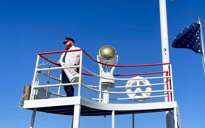 Captain on deck of the Steamboat Natchez with megaphone and flag.