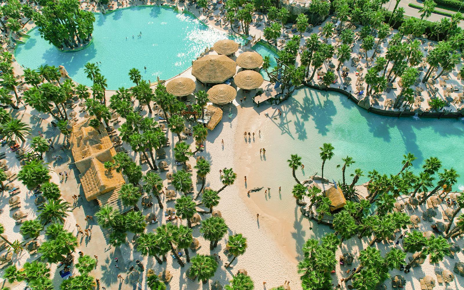 Aerial view of Caribe Bay with palm trees, sandy beaches, and turquoise pools.