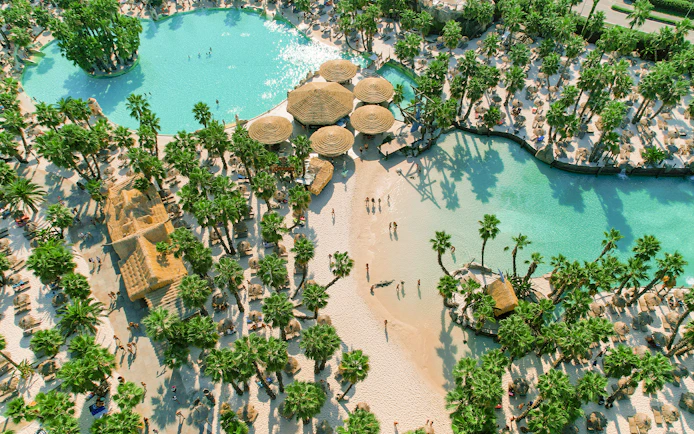 Aerial view of Caribe Bay with palm trees, sandy beaches, and turquoise pools.