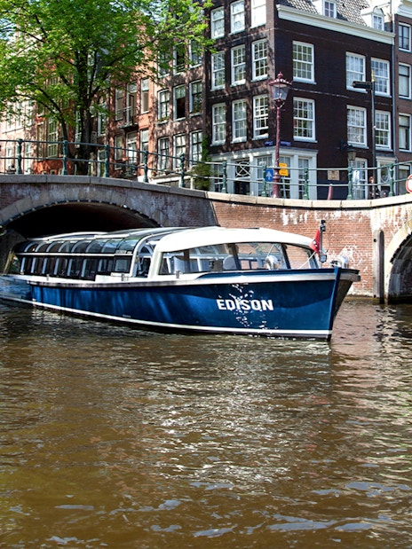 Canal cruise boat passing under a bridge in Amsterdam.