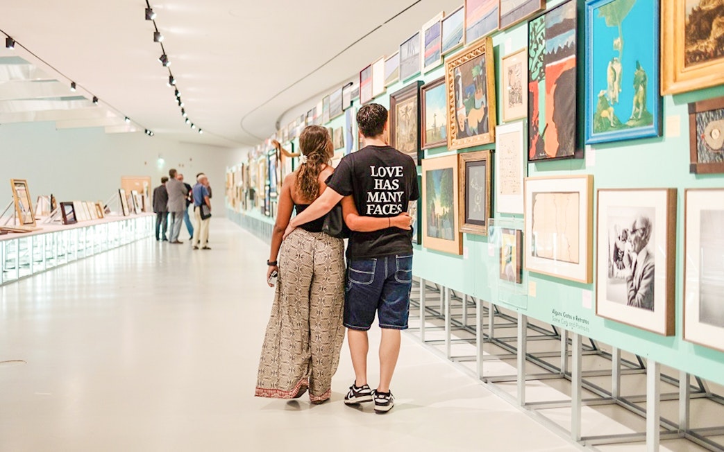 Couple walking through MAAT Gallery, Lisbon, viewing art exhibits.
