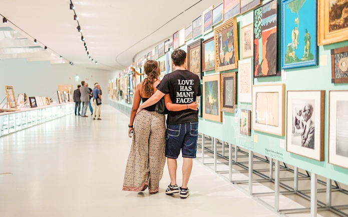 Couple walking through MAAT Gallery, Lisbon, viewing art exhibits.