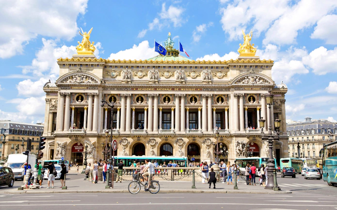 Palais Garnier facade with people and traffic, Paris walking tour.