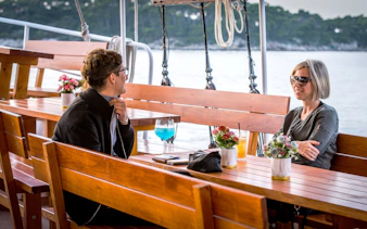 People enjoying cocktails on a boat with scenic water view.