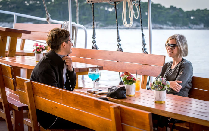 People enjoying cocktails on a boat with scenic water view.