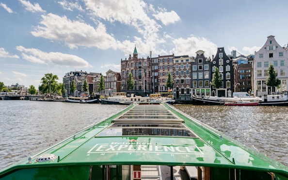 Heineken cruise boat on Amsterdam canal with historic buildings in the background.