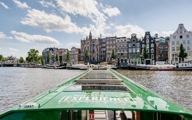 Heineken cruise boat on Amsterdam canal with historic buildings in the background.