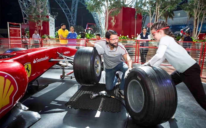 Visitors changing tires on a Formula 1 car at Ferrari World, Yas Island, Abu Dhabi.