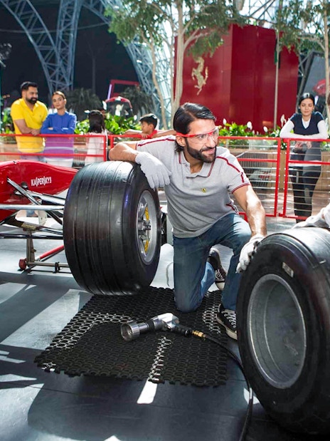 Visitors changing tires on a Formula 1 car at Ferrari World, Yas Island, Abu Dhabi.