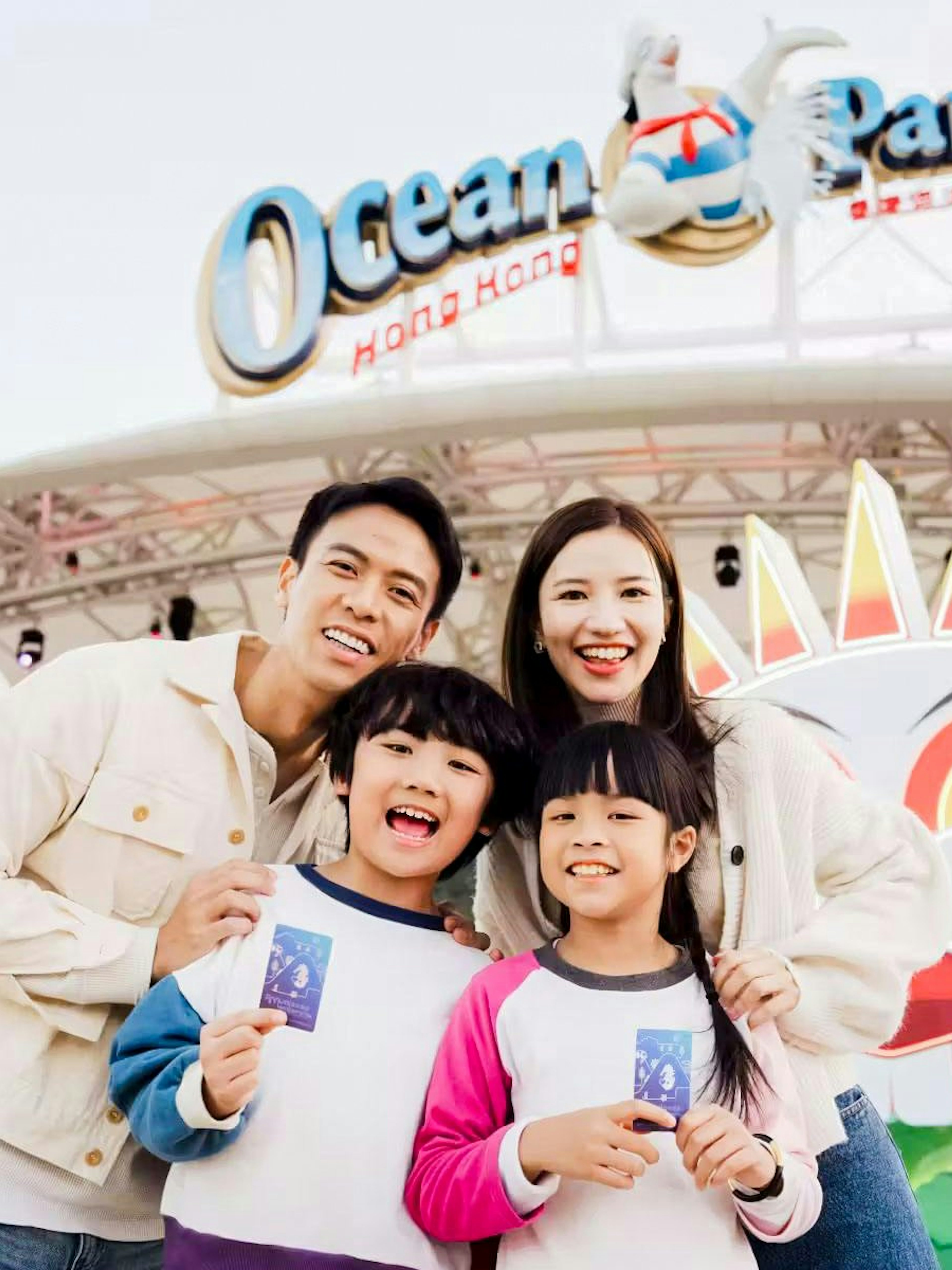 Family of four smiling in front of Ocean Park entrance, Hong Kong.