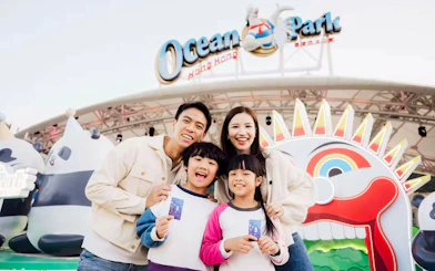 Family of four smiling in front of Ocean Park entrance, Hong Kong.